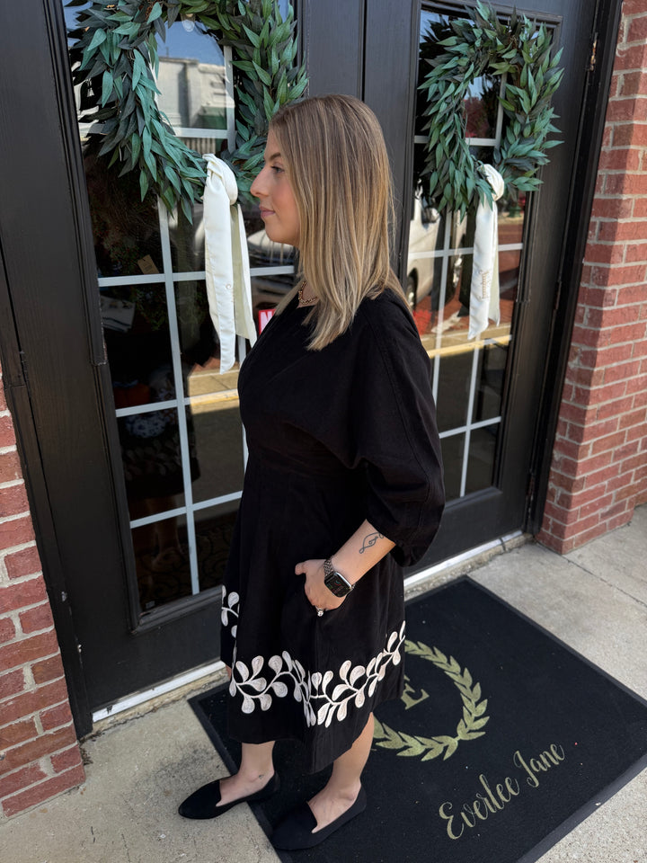 Black corduroy Vine Embroidered Dress with three-quarter sleeves and white vine hem. Sizes available.