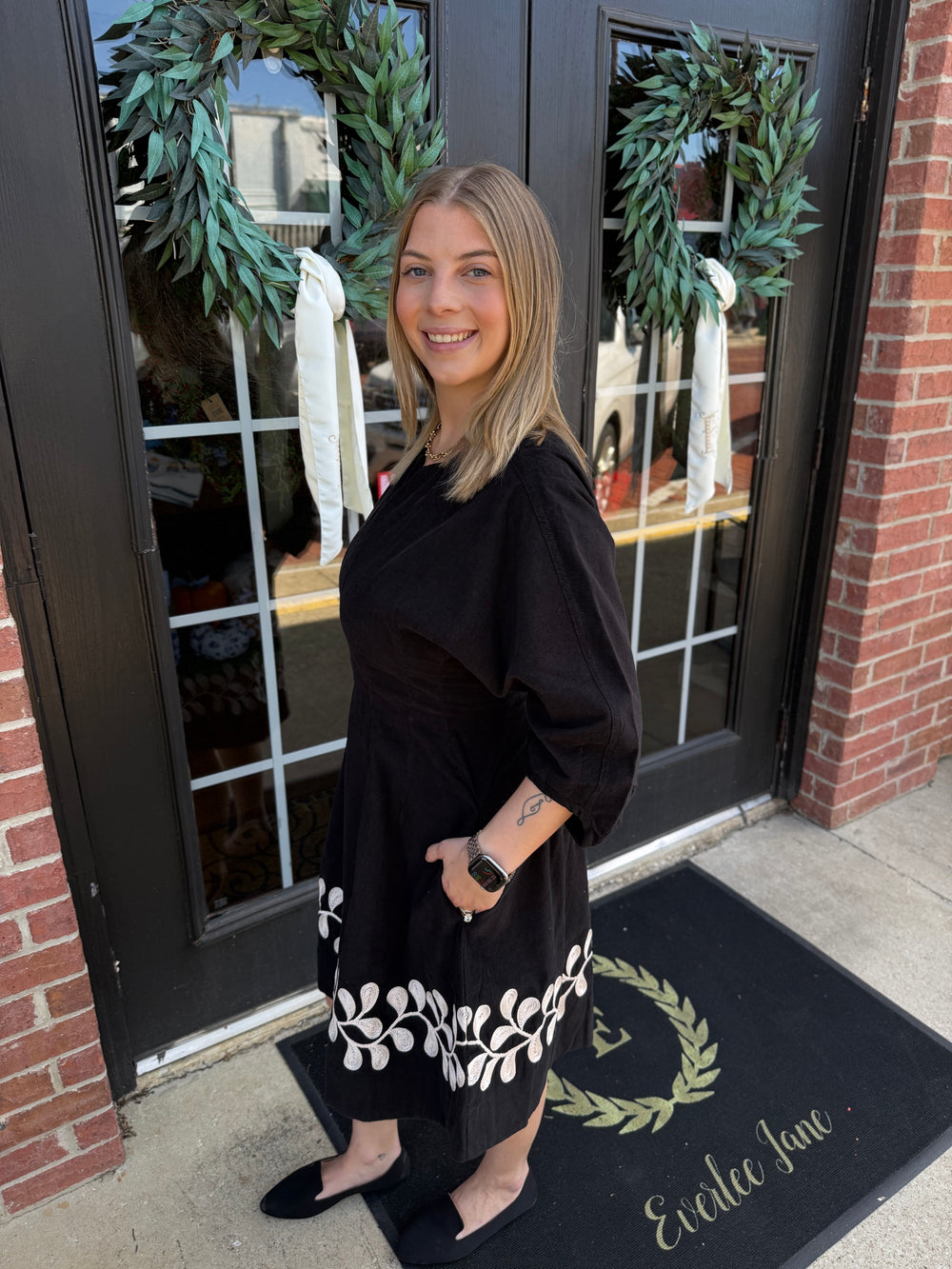 Vine Embroidered Dress in black corduroy with white vine embroidery at hem and three-quarter sleeves. Available in all sizes.