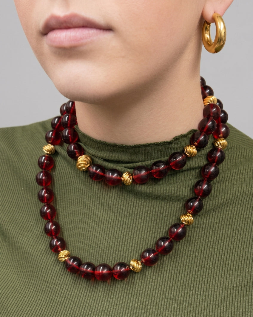 Ravello 5-in-1 Gold Necklace in cranberry, a long gold-plated piece featuring alternating translucent beads and small ridged spheres, worn doubled as an adjustable length accessory.