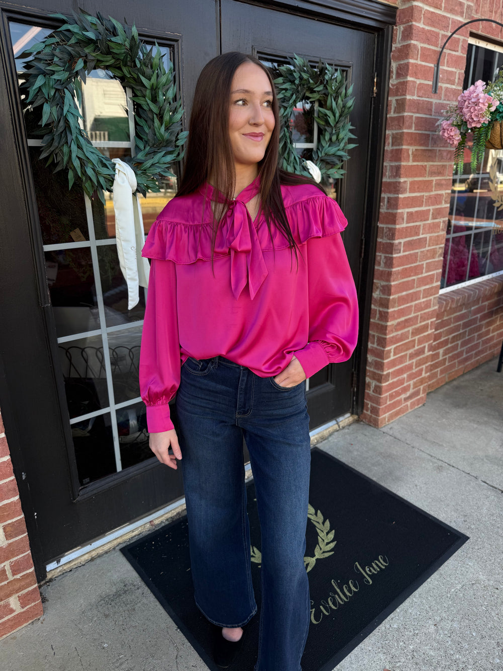 Fuchsia silky bow neck top with long sleeves, a ruffled yoke, and a bow neck tie. Available in various sizes.