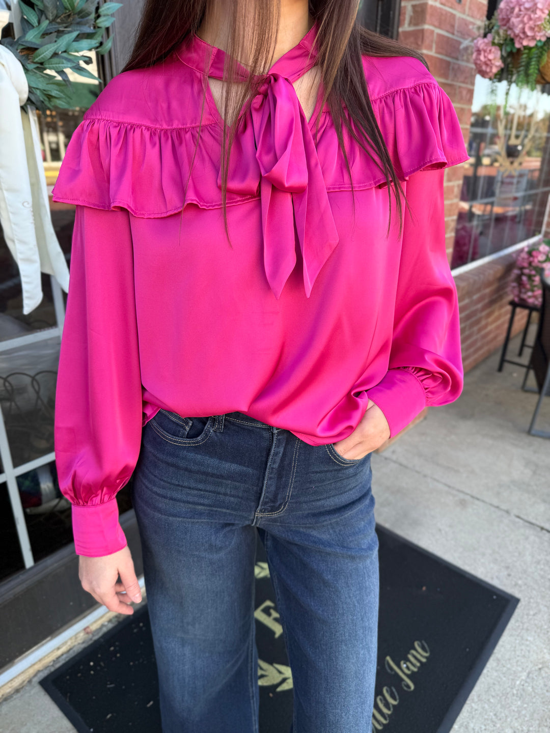 Bright fuchsia silky bow neck top with a ruffled yoke. Available in all sizes.