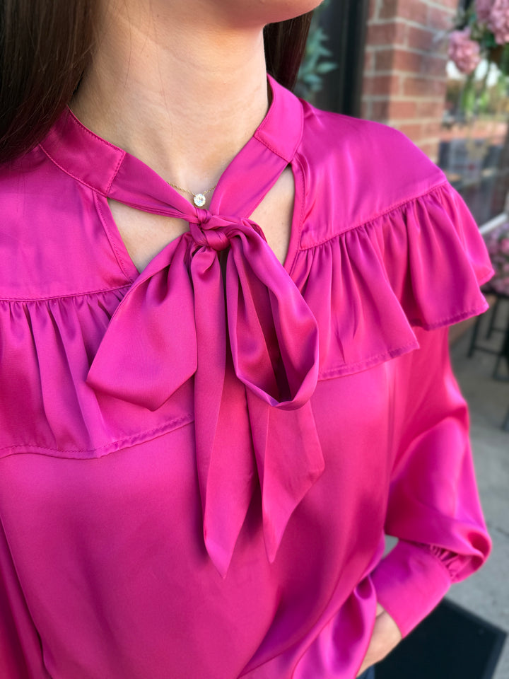 Fuchsia silky long-sleeve top with bow neck and chest ruffle. Sizes available.
