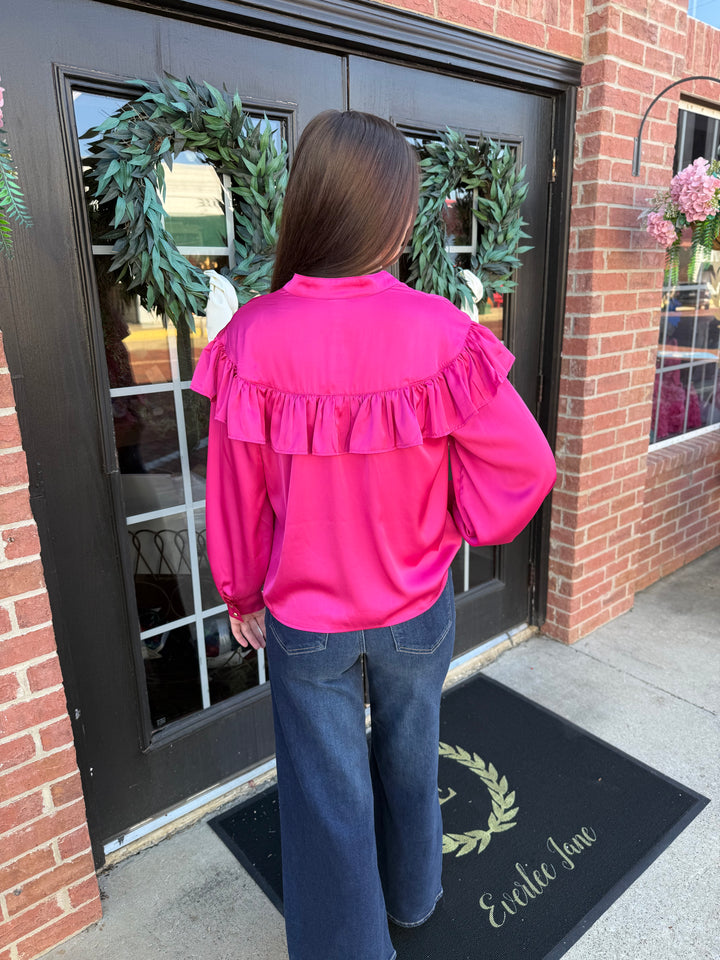 Fuchsia silky long-sleeved blouse with ruffled collar and bow neck.