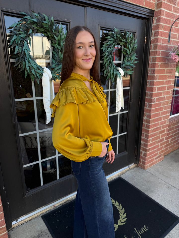 Chartreuse silky long-sleeve top with ruffled yoke and bow neck tie. Available in various sizes.