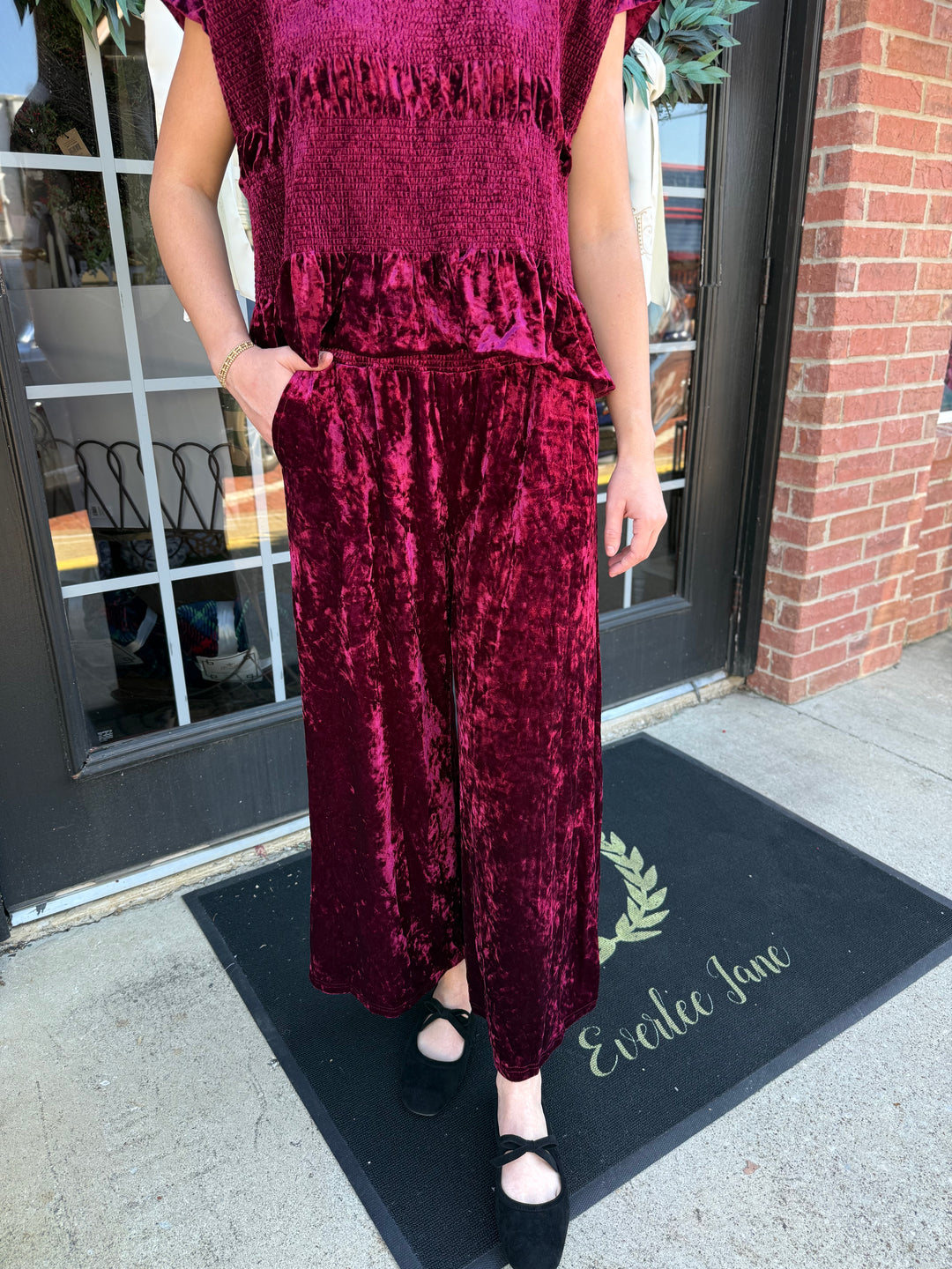 Cranberry crushed velvet wide-leg pant with a smocked waistband and side pockets.