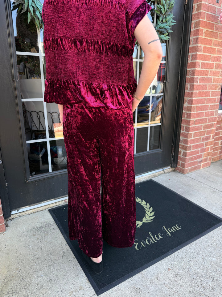 Cranberry crushed velvet wide-leg pants with a flowy silhouette.