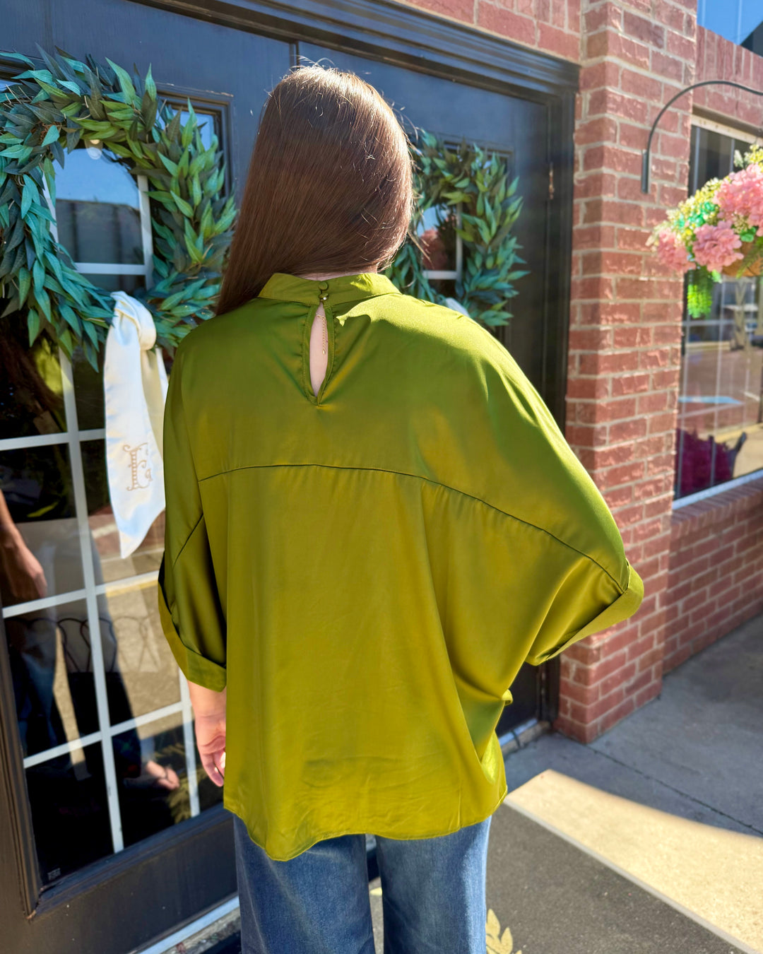 Olive green oversized satin mock neck top with three-quarter length sleeves and back button closure. Available in multiple sizes.