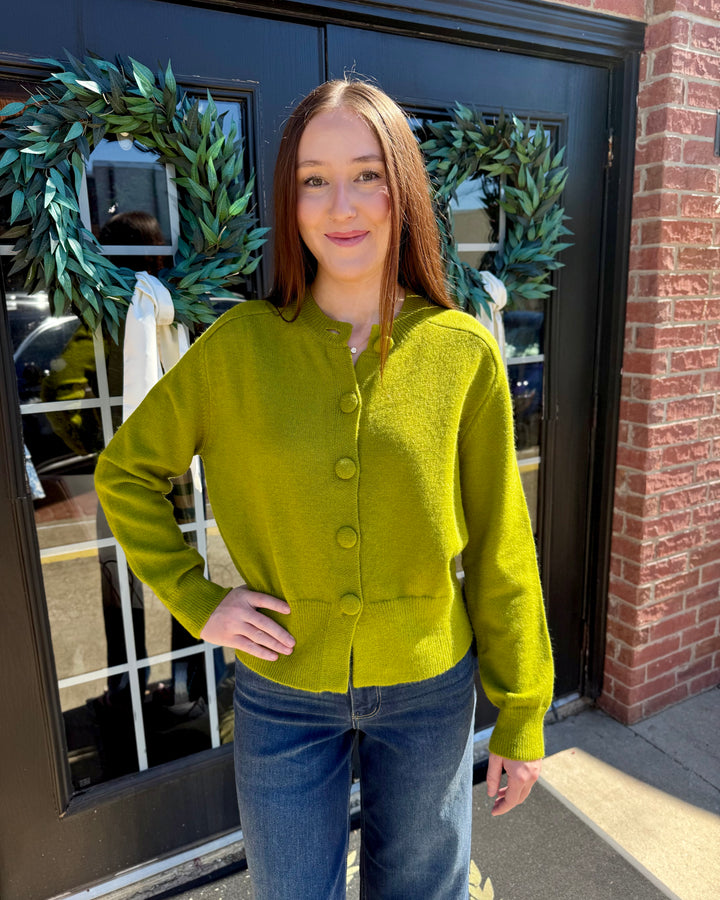 Olive green button-up cardigan with long sleeves, crew neck, and button-front closure. Available in sizes.