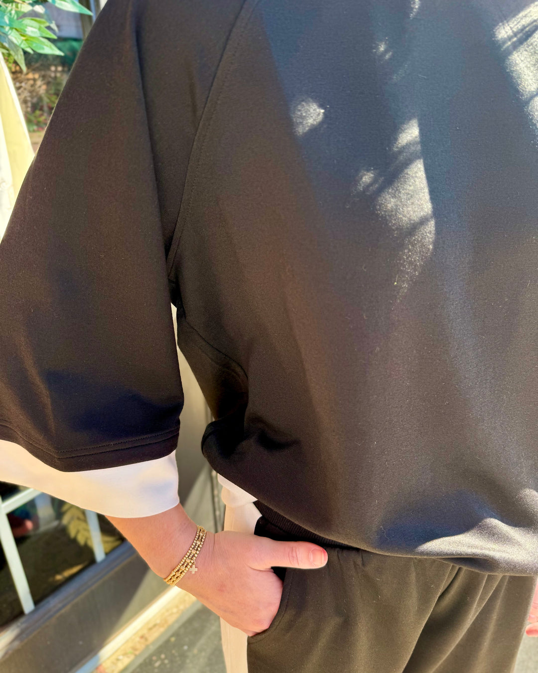 Black colorblock crewneck raglan sleeve top with white cuffs.