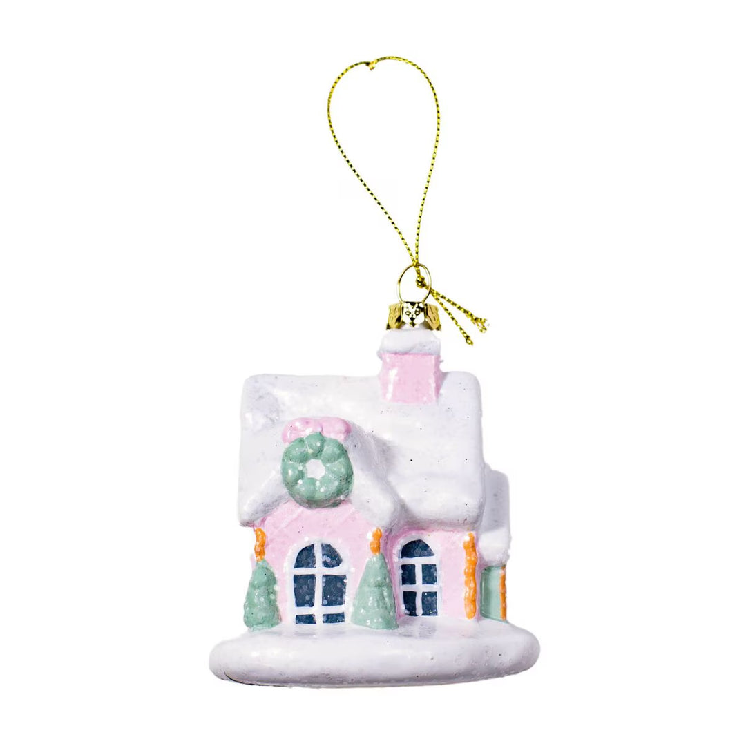 Winter Dreams pink house ornament with snow-covered roof, door wreath, and gold hanging string.