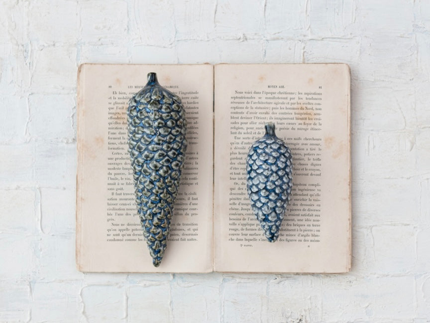 Two blue stoneware pinecone ornaments.