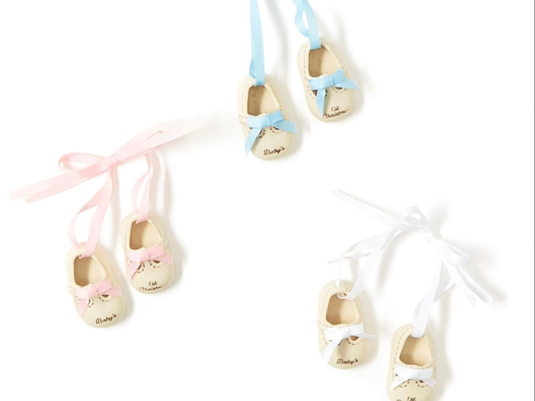 Three pairs of Baby’s 1st Christmas shoe ornaments with pink, blue, and white ribbons.