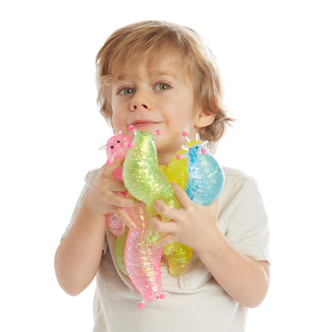 Four colorful, translucent, glittery Squishy Glitter Slug toys.