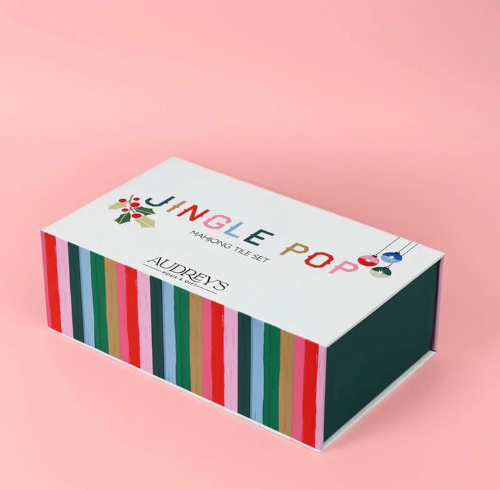 Jingle Pop Christmas Mahjong set rectangular box with holiday ornament and holly graphics and vertical striped sides.