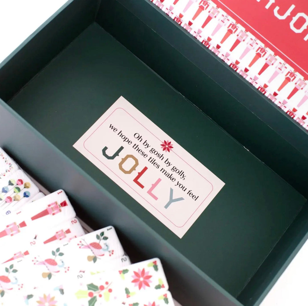 Dark green Christmas Mahjong set with a box featuring a “Oh by gosh by golly, we hope these tiles make you feel JOLLY” sticker and patterned tiles.