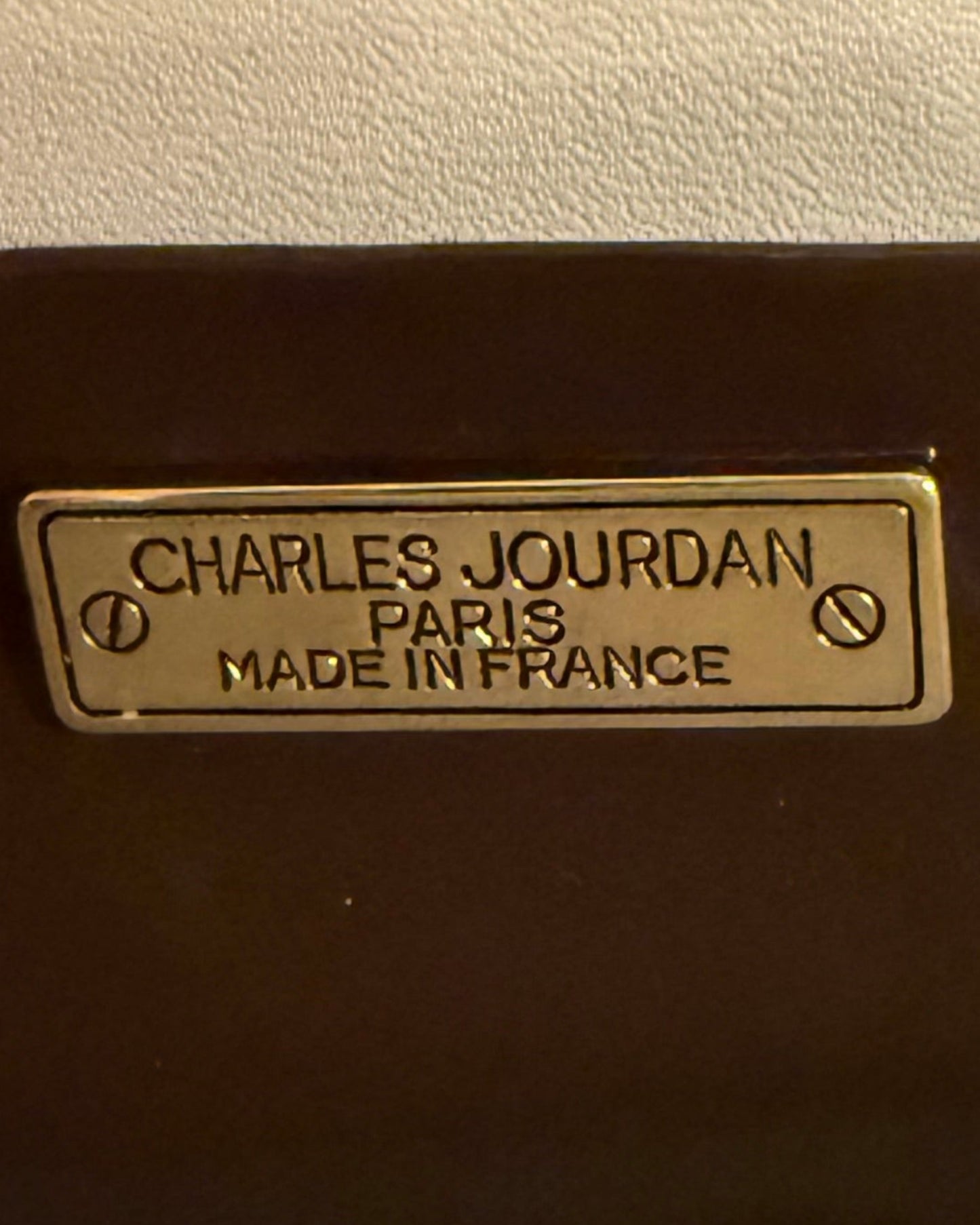 Metal label reading “CHARLES JOURDAN PARIS MADE IN FRANCE,” secured with two screws, on Vintage Charles Jourdan Paris Genuine Alligator Clutch. Sizes available: not specified.