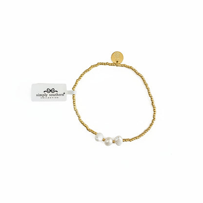 Stretch gold beaded bracelets with three white pearls, round gold charm, and "simply southern" tag. Sizes: S/M, M/L.