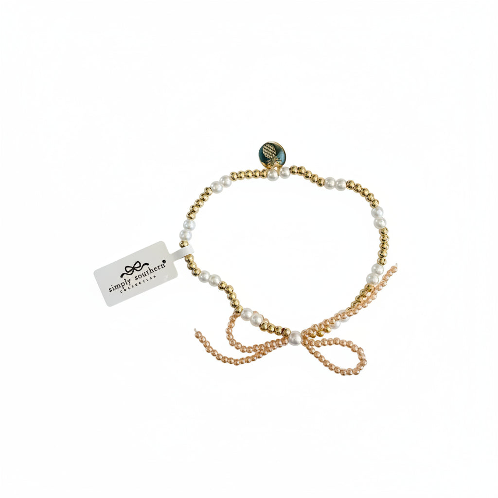 Gold and pearl-like beaded bracelet with accent beads, tied bow, charm, and "simply southern" tag. Sizes: S/M, M/L.