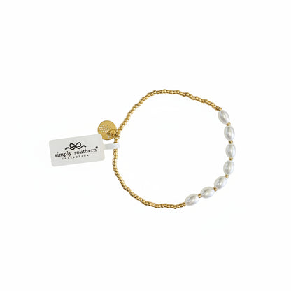 Gold beaded bracelet with white oval pearls, gold charm, and “simply southern collection” tag. Sizes: S/M, M/L.