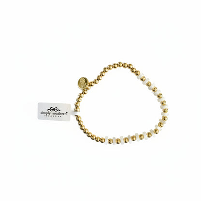 Gold beaded bracelet with white "MAMA" letter beads and round charm. Available in S, M, L.