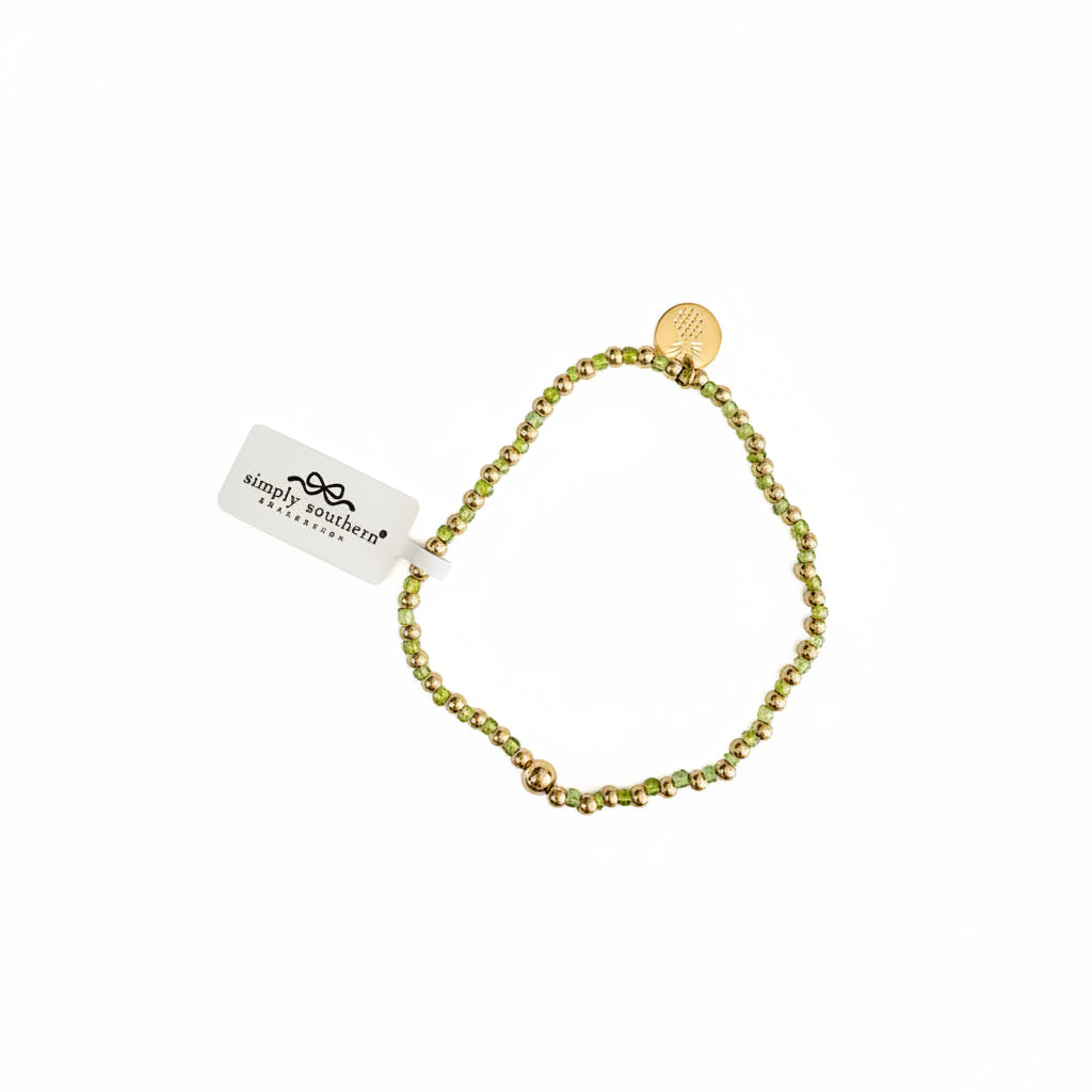 Gold beaded bracelets with green and gold accents, round gold charm, and white “simply southern” tag. Sizes: S, M, L.