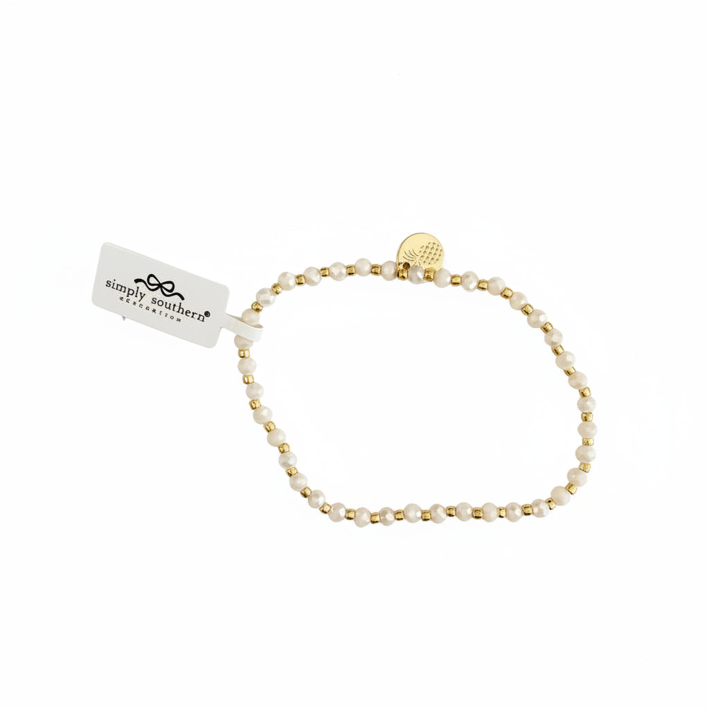 Gold beaded bracelet with alternating white beads, small gold charm, and "simply southern" tag. Available in S, M, L.
