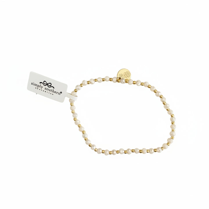 Gold beaded bracelet with alternating white beads, small gold charm, and "simply southern" tag. Available in S, M, L.