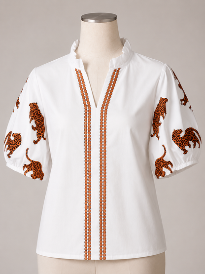 Off-white top with puff sleeves, ruffled collar, leopard embroidery, orange beaded stripes. Sizes: S-XL.