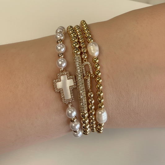 Set of four gold and pearl stretch beaded bracelets with cross charm and bar accent. Available in S, M, L sizes.