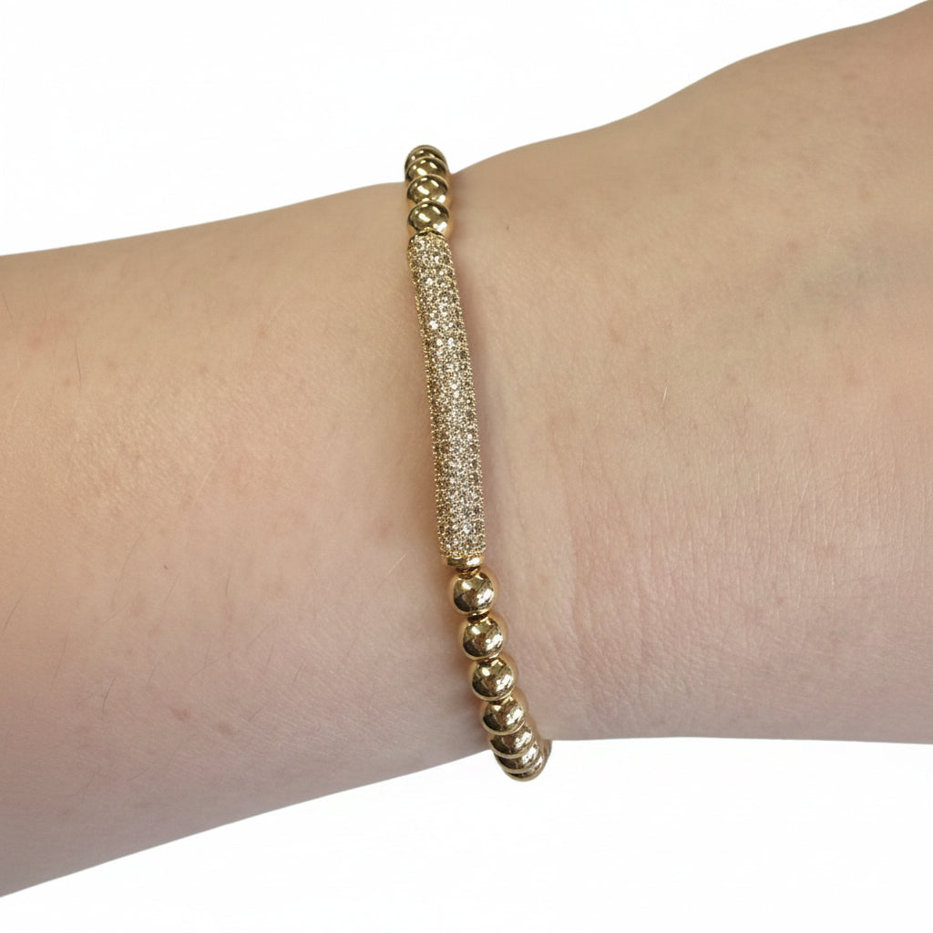 Beaded Gold Stretch Bracelets with a textured cylindrical bar centerpiece on a gold beaded band. Available in S, M, L.