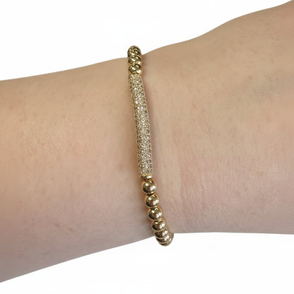 Beaded Gold Stretch Bracelets with a textured cylindrical bar centerpiece on a gold beaded band. Available in S, M, L.