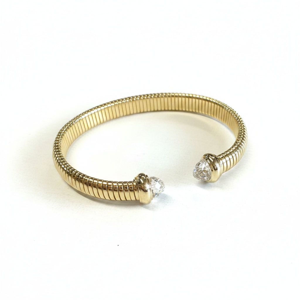 Stainless steel gold dipped cuff bracelet with ribbed texture, clear cubic zirconia ends. Sizes: S, M, L.