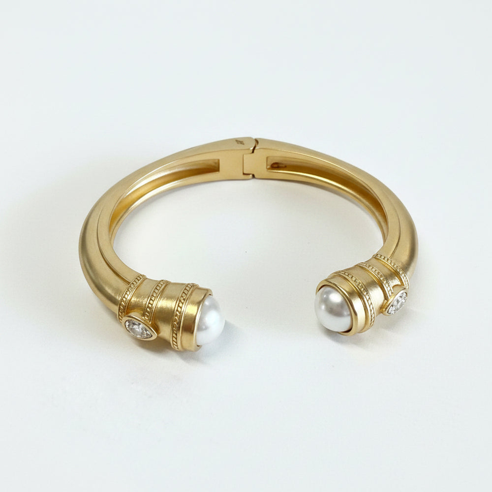 Gold-dipped stainless steel cuff with rounded ends, each set with a large white pearl and small diamonds. Sizes: S, M, L.