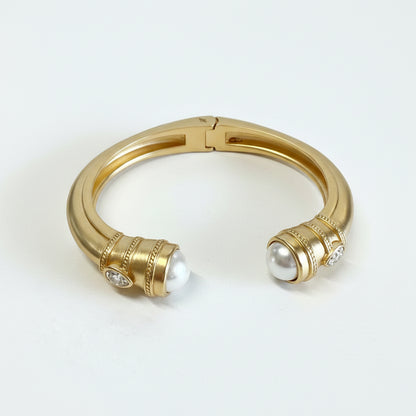 Gold-dipped stainless steel cuff with rounded ends, each set with a large white pearl and small diamonds. Sizes: S, M, L.