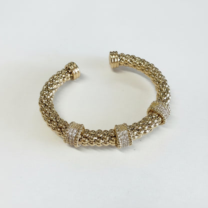 Stainless steel gold dipped cuff bracelet with three cubic zirconia bands. Available sizes: S, M, L.