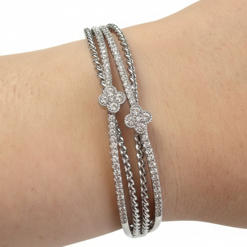 Three intertwined silver bands with CZ stones and floral accents. Available sizes: S, M, L.