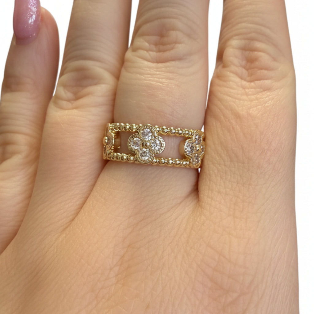 Gold ring with beaded edges and three diamond-studded floral designs. Available in sizes 5–9.
