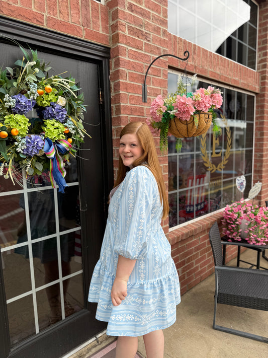 Riley Tulip Tapestry Blue Dress with 3/4 sleeves, tiered skirt, and light blue pattern; available in sizes XS-XL.