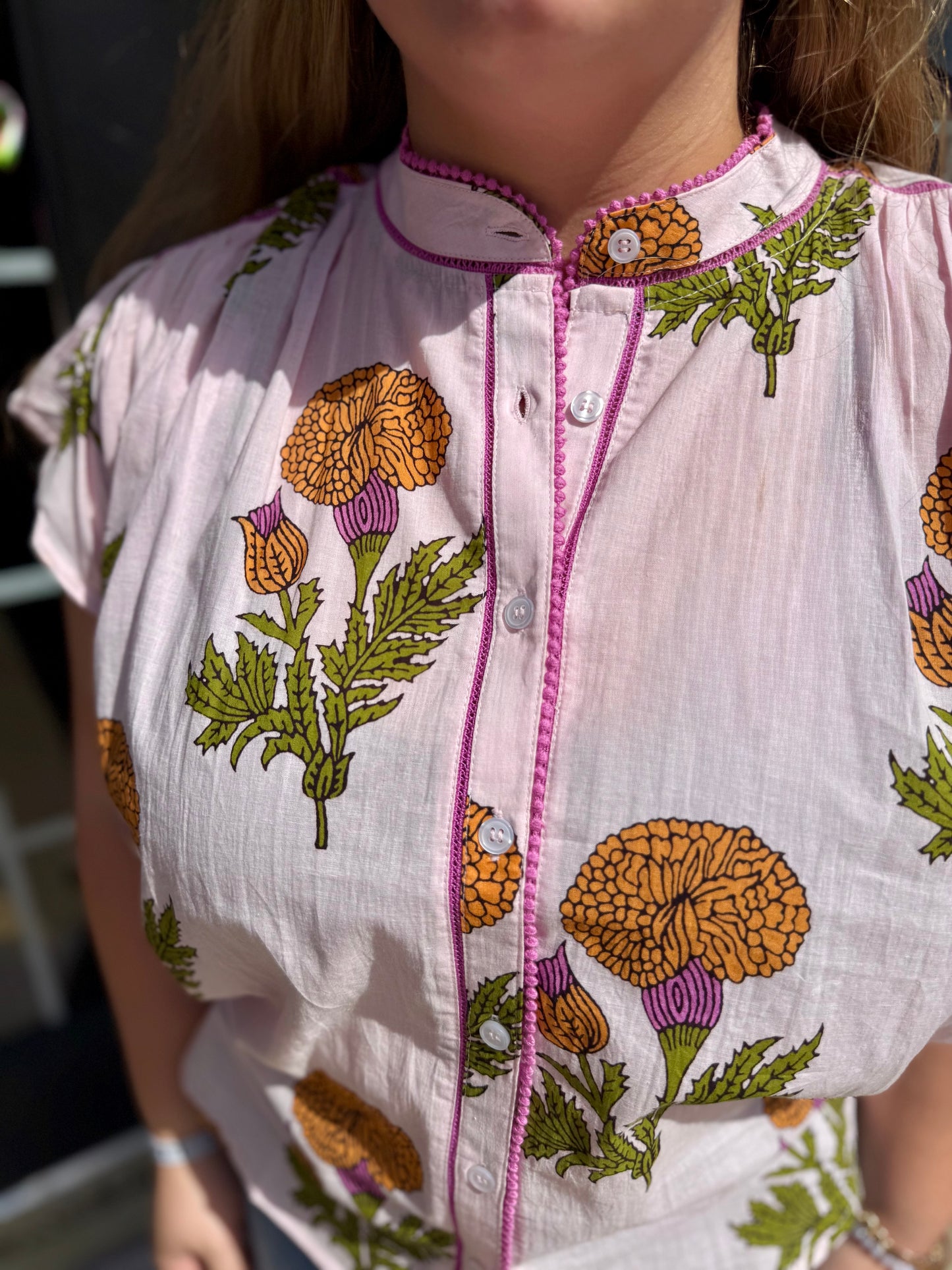 Fem De La Fleur Top: light pink floral cotton blouse with orange, purple, green print, button-up front, pink trim. Sizes XS-XL.