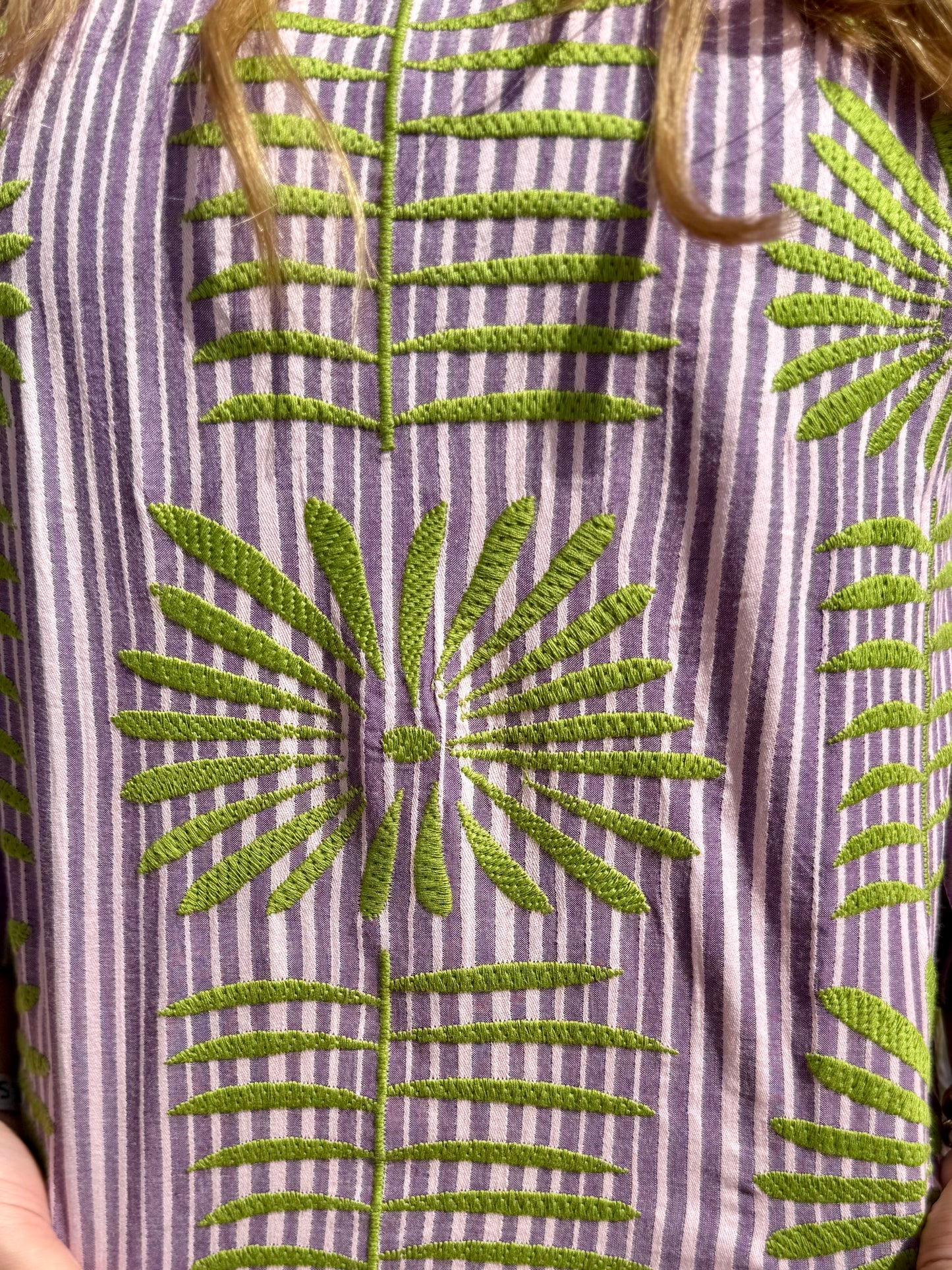 Close-up of Purple Elena Blouse: vertical purple/white stripes, green embroidered leaves/flowers. Sizes: XS-XL.