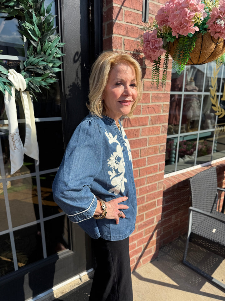 Ellie Washed Denim Floral Top with 3/4 sleeves and white floral appliqué, available in sizes S-XL.