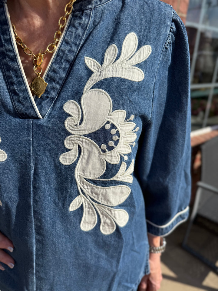 Ellie Washed Denim Floral Top with 3/4 sleeves and white floral embroidery, available in sizes XS-XL.