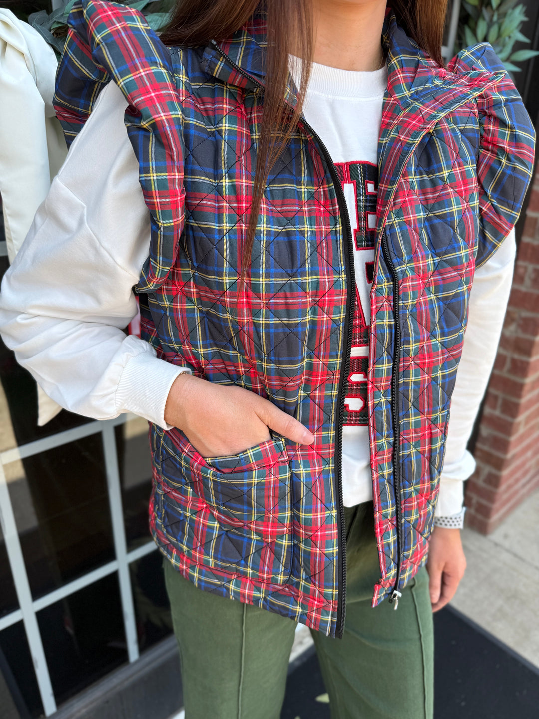 Plaid Tidings Puffer vest shown with hand in pocket; available in sizes XS-XL.