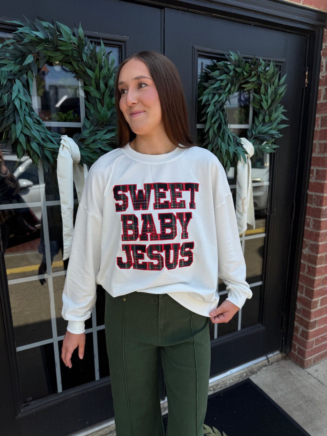 White long-sleeve Sweet Baby Jesus crew neck sweatshirt with red and black plaid lettering.