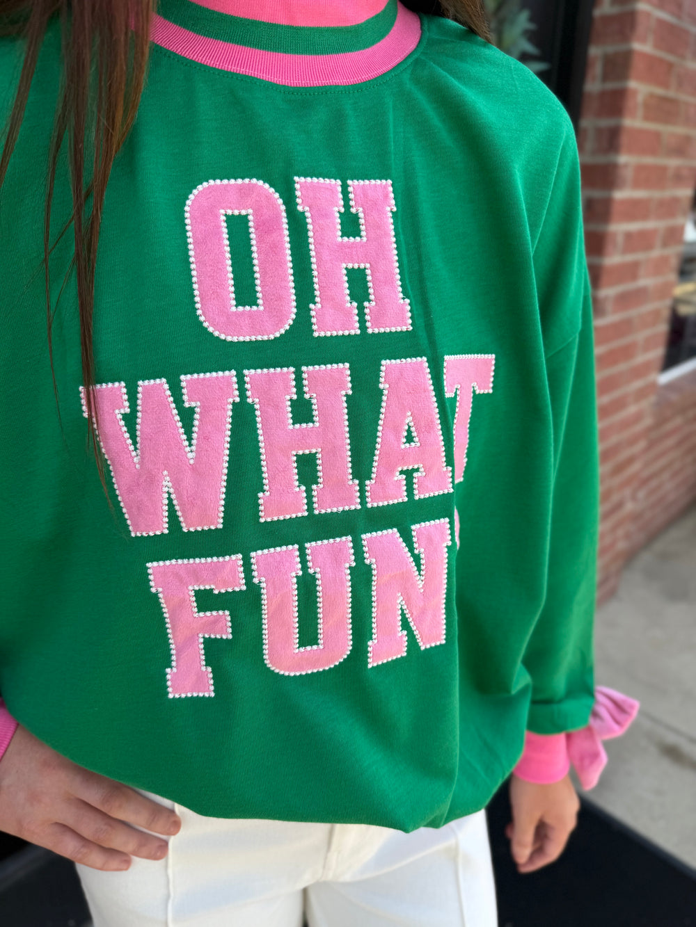 Green mock neck sweatshirt with pink trim and “OH WHAT FUN” in pink beaded-outline block letters. Available in multiple sizes.