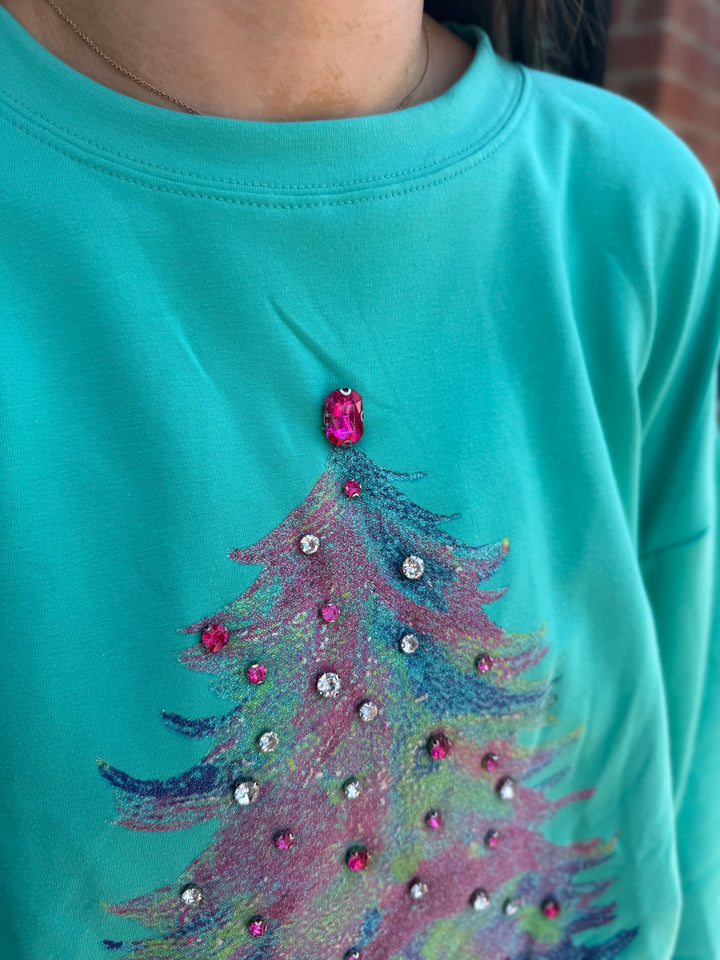 Teal long-sleeve gemstone Christmas tree sweatshirt with a pastel printed tree and pink and clear gemstone embellishments. Available in various sizes.