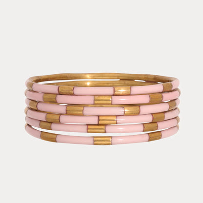 Six enamel bangles with alternating shiny gold and light pink segments. Available in small, medium, and large sizes.