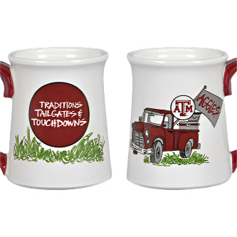 White TAMU Traditions Mugs with red handles, “TRADITIONS TAILGATES & TOUCHDOWNS” on one side, red truck with Aggies flag on other. Sizes: 11oz, 15oz.