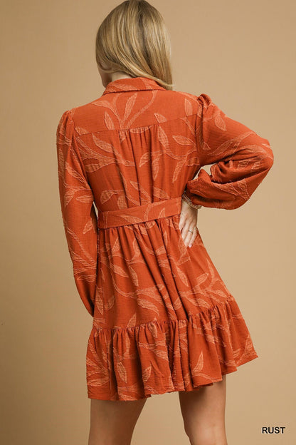 Piper Jacquard Dress with Tie Waist, rust color, long sleeves, leaf pattern. Available in sizes XS-XL.