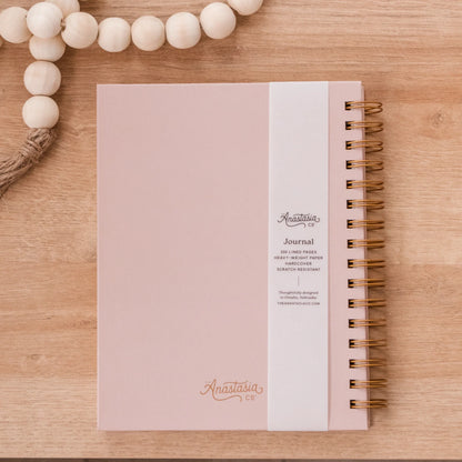 Pink, scratch-resistant spiral hardcover journal with "Anastasia" in cursive and lined pages. Available sizes: not specified.